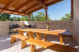 - une table de pique-nique en bois sur une terrasse avec barbecue dans l'établissement Villa Rosa Kringa, à Tinjan