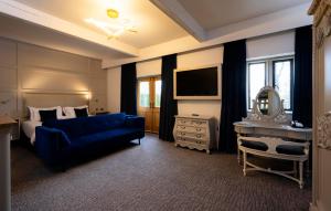 ein Schlafzimmer mit einem blauen Sofa, einem Bett und einem Spiegel in der Unterkunft Stanley House Hotel & Spa in Blackburn