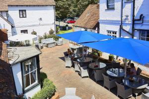 a patio with tables and chairs with blue umbrellas at The George Hotel in Wallingford