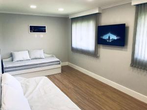 1 dormitorio con 1 cama y TV en la pared en Conforto na Serra de Teresópolis, en Teresópolis