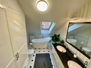 uma casa de banho com uma banheira e 2 lavatórios e uma banheira em Apartament Szafarnia DeLux em Gdansk
