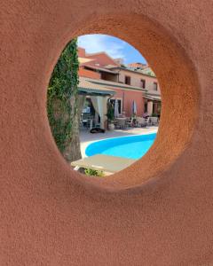 - une vue sur la piscine à travers un trou dans un bâtiment dans l'établissement Hotel Corallaro, à Santa Teresa Gallura