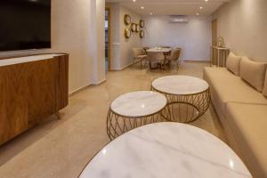 een woonkamer met 2 tafels en een bank bij Appartement luxueux Coralia avec piscine in Marrakesh