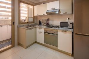 a kitchen with white cabinets and a sink and a microwave at Appartement luxueux Coralia avec piscine in Marrakech
