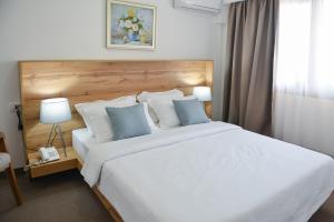 1 dormitorio con 1 cama blanca grande con almohadas azules en Magnolia Place, en Tivat