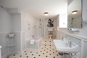 bagno bianco con lavandino, vasca e servizi igienici di Dunster Mill House a Dunster
