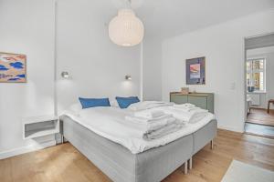 コペンハーゲンにあるNABO Hotel Apartmentsの白いベッドルーム(青い枕の大型ベッド付)
