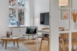NABO Hotel Apartments في كوبنهاغن: غرفة معيشة مع طاولة وكراسي وتلفزيون