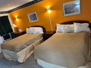 2 camas en una habitación de hotel con paredes amarillas en sunrise motel, en Owego