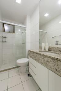 La salle de bains blanche est pourvue d'une douche et de toilettes. dans l'établissement Cabo Frio com conforto e estilo!!!, à Cabo Frio