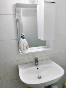 een witte wastafel in een badkamer met een spiegel bij Marios IsimeriaHomz in Thessaloniki