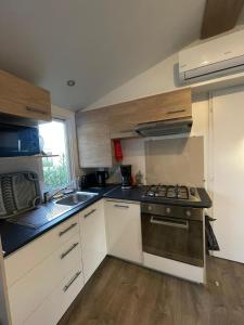 a small kitchen with a stove and a sink at Mobil home 6 à 8 personnes SANS Fun Pass in Canet-en-Roussillon