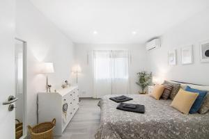 a white bedroom with a bed and a dresser at Apartamento Acácia in Vale do Lobo