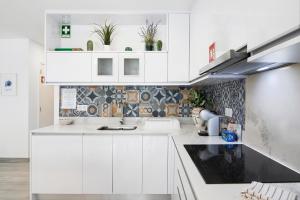 - une cuisine blanche avec des placards blancs et un évier dans l'établissement Apartamento Acácia, à Vale do Lobo