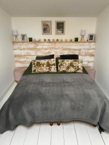 a bedroom with a bed with a black blanket and pillows at Le Petit Chai Fronsadais in Saint-Michel-de-Fronsac