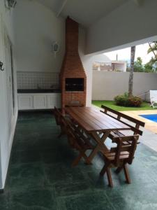 patio z drewnianym stołem i krzesłami oraz kominkiem w obiekcie Costa Verde Tabatinga, Caraguatatuba w mieście Caraguatatuba