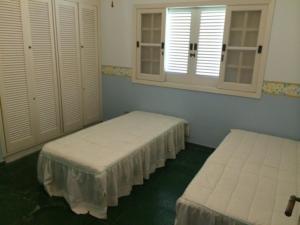 2 łóżka w pokoju z białymi ścianami i oknami w obiekcie Costa Verde Tabatinga, Caraguatatuba w mieście Caraguatatuba