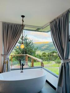 ein großes Bad mit einer Badewanne und einem großen Fenster in der Unterkunft ALTITUDE MÁXIMA - Cabanas de Altitude in Urubici