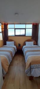 Duas camas num quarto com janelas e pisos em madeira em Posada SAQRA Cusco em Cusco