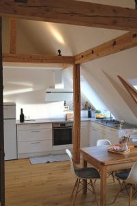 an attic kitchen with white cabinets and a wooden table at Helles modernes City-Loft in Freudenstadt