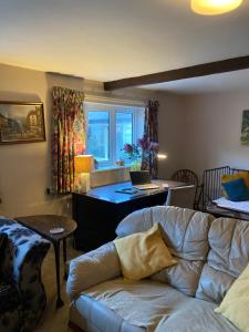 a living room with a couch and a desk with a laptop at Charming Pretty cottage in Banbury