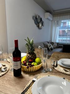 a table with a bottle of wine and a bowl of fruit at Sunshine Homes Zamárdi in Zamárdi