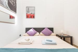 um quarto branco com uma cama com almofadas roxas em L'Appartamentino Holiday Home em Lecce