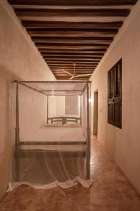 an empty bed in a room with a ceiling at Amma's House in Lamu