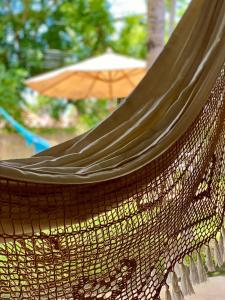 a hammock with an umbrella in the background at Casa de Praia em Japaratinga-AL in Japaratinga