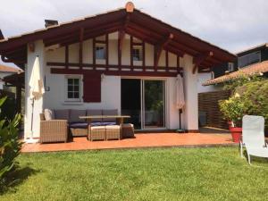 a patio with a table and chairs in a yard at 1km plage, agréable maison 6 pers classée 3* in Hendaye