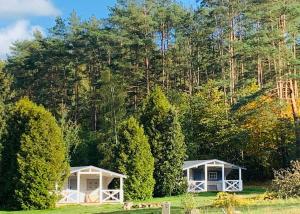 dos cabañas blancas en un campo con árboles en Domki w Lesie en Silnowo