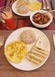 um prato de pequeno-almoço com ovos e pão numa mesa em AYIRA Maldives em Feridhoo