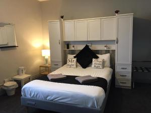 マンチェスターにあるQueens Guesthouse Manchesterのベッドルーム1室(大型ベッド1台、白いキャビネット付)