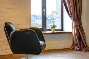 a black chair sitting in front of a window at Loft 65 66 Panoramic View in Vilnius