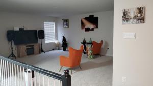 528 Carroll Walk Avenue في فريدريك: غرفة معيشة مع كراسي برتقالية وتلفزيون