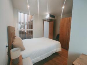 a bedroom with a white bed and a window at Casa Pintáns in Cangas de Morrazo