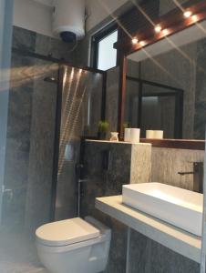 a bathroom with a toilet and a sink and a mirror at Aura Residence in Katugastota