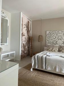 a white bedroom with a bed and a mirror at Chambres d'Hôtes Villa La Louisiane in Arès