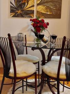 una mesa con sillas y un jarrón de rosas rojas en Royal Place Apartment - East Sarajevo, en Lukavica