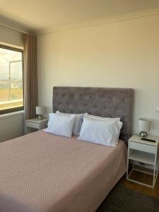 Un dormitorio con una cama con almohadas blancas y una ventana en A MINHA ALEGRE CASINHA en Aveiro