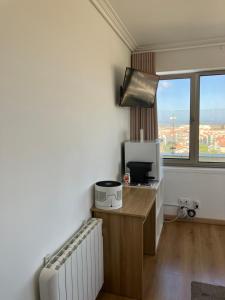 a room with a desk with a microwave and a window at A MINHA ALEGRE CASINHA in Aveiro