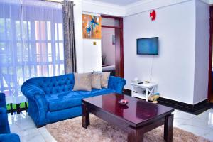 a living room with a blue couch and a coffee table at Rozy Penthouse in Kisumu