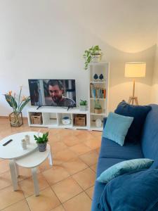 een woonkamer met een blauwe bank en een tv bij Farfalla in San Vito lo Capo