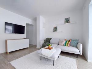 a white living room with a couch and a tv at Modern and cosy apartment in Lahemaa national park in Kolga