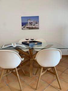 een glazen tafel met twee stoelen en twee wijnglazen bij Farfalla in San Vito lo Capo