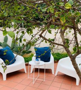 een patio met 2 stoelen, een tafel en een boom bij Farfalla in San Vito lo Capo