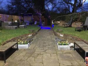 a garden with two benches and flowers in a yard at Queens Guesthouse Manchester in Manchester