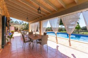 een patio met een tafel en stoelen en een zwembad bij Sa ROTA in Santa Margarita