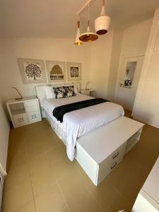 a bedroom with a large white bed and a white table at Golden Beach House in Porto Santo