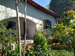 uma pequena casa branca com janelas azuis num jardim em Casa dos Buritis-no centro turístico em Alto Paraíso de Goiás